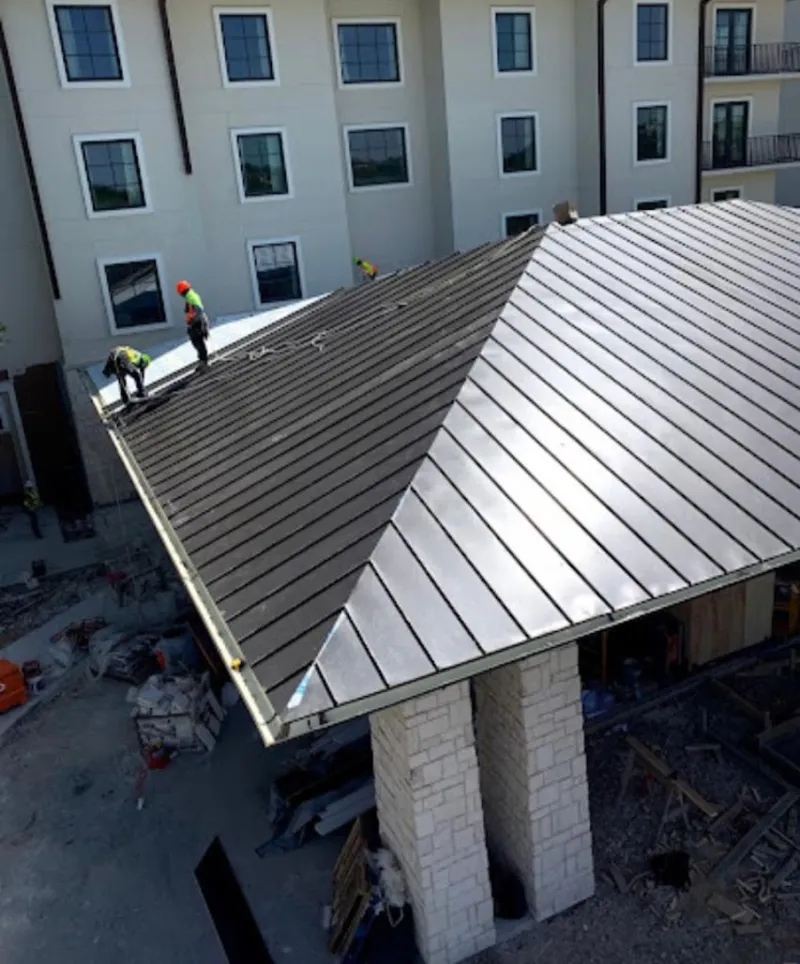 Crew installing standing seam metal roof panels on a commercial project in Fox Chapel